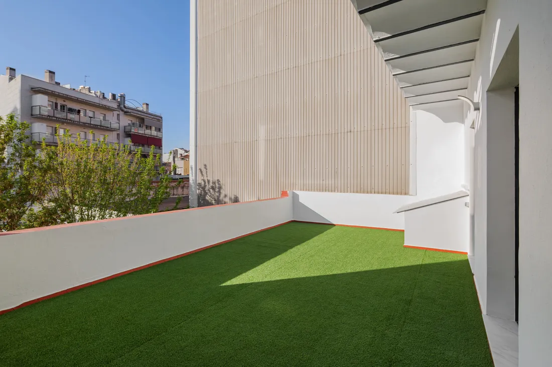 Artificial turf laid across a paved courtyard, finished neatly against the hard edge