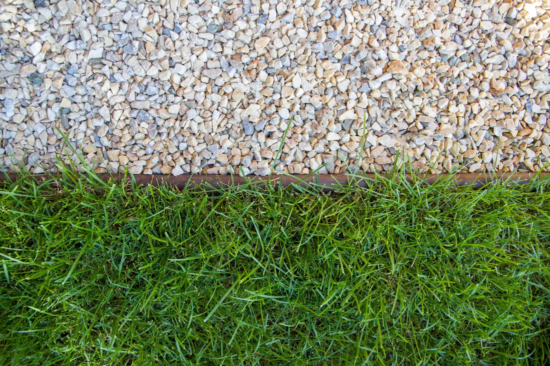 Artificial turf meeting a decorative pebble drainage border